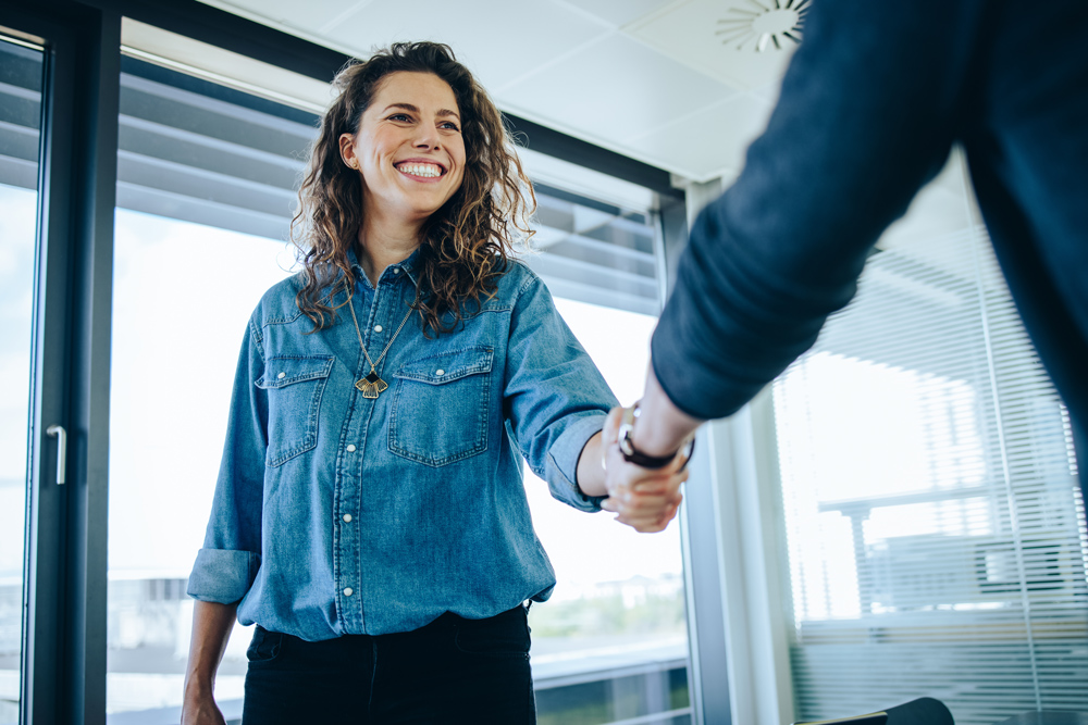 Recruitment manager shaking hands with male candidate in an office